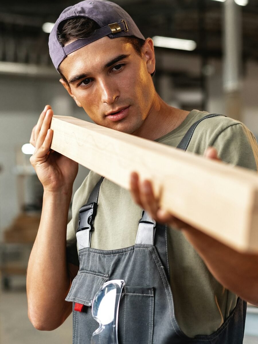 Young carpenter man looking and choosing wood plank at workshop in carpenter wood factory